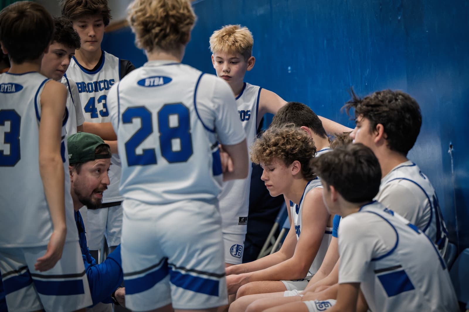 A Broncos team huddling with their coach during a timeout