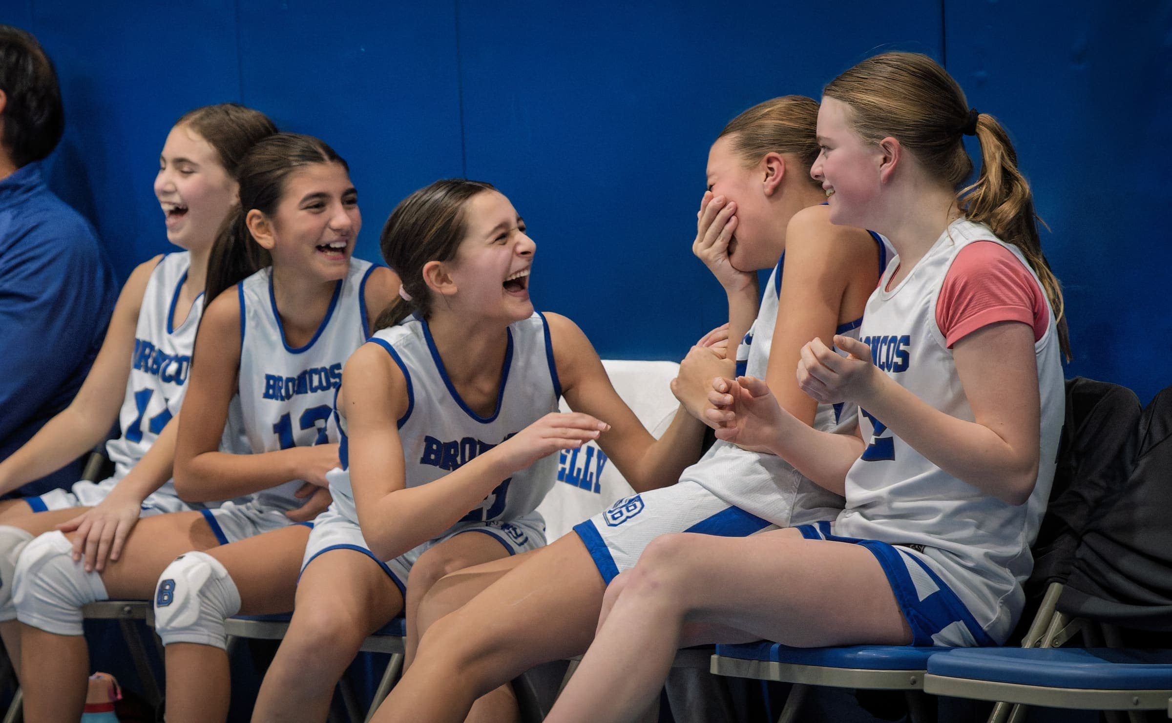 BYBA girls sharing a laugh on the bench during a game