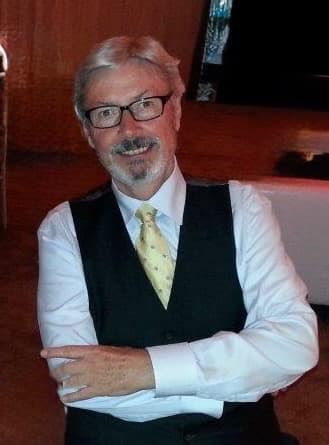 John Cooke smiling in a vest and tie